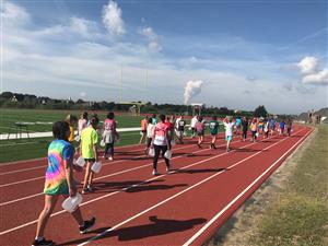 6th grade students walk the school track with jugs of water 