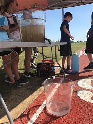 Students filling jugs with dirty water 